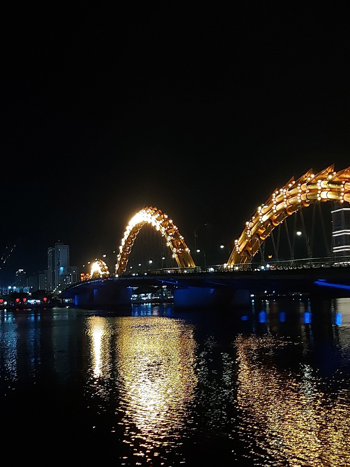 Dragon Bridge glows gold over Da Nang at night