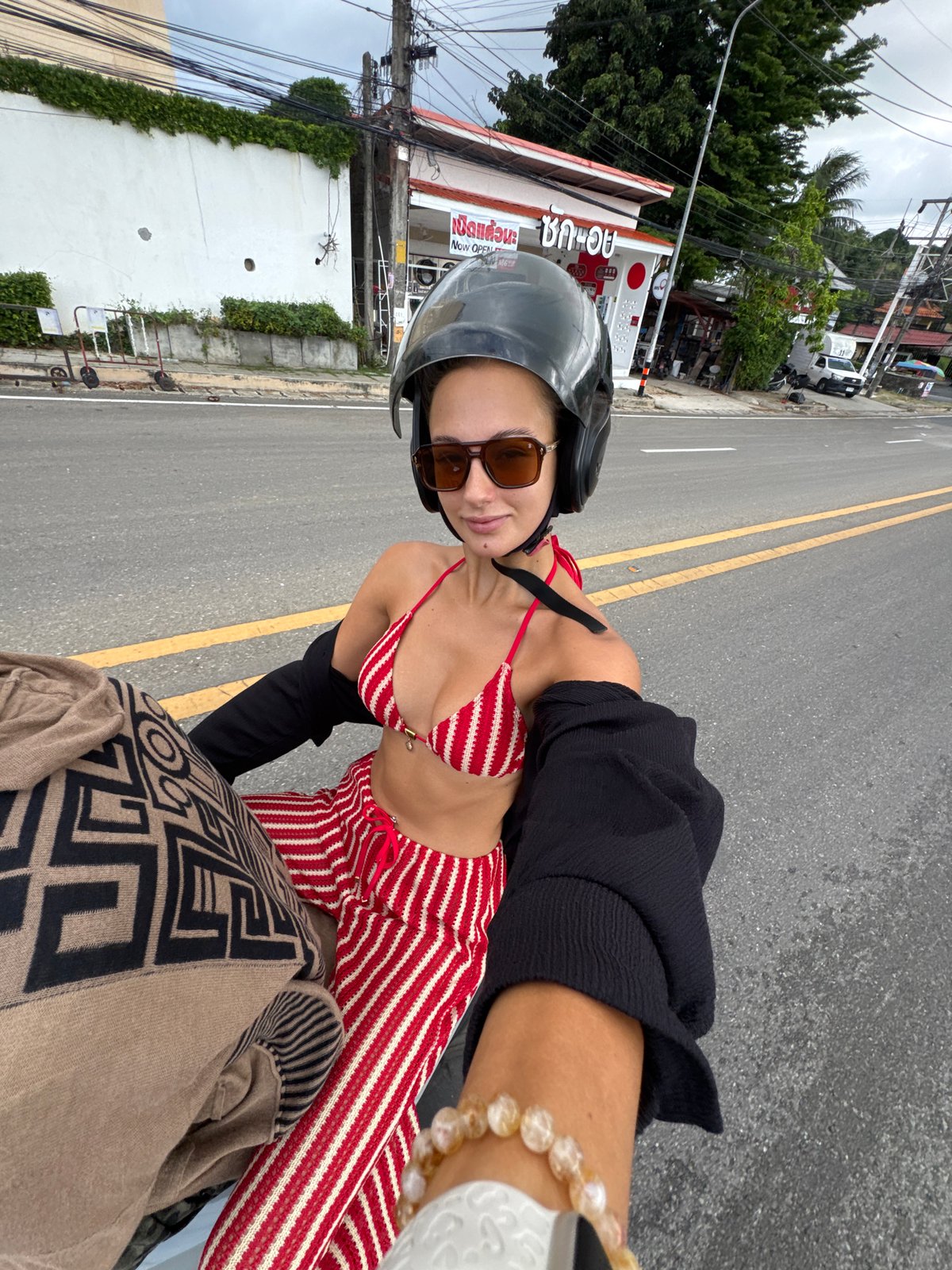Woman in bikini top rides motorcycle on wet Rawai road