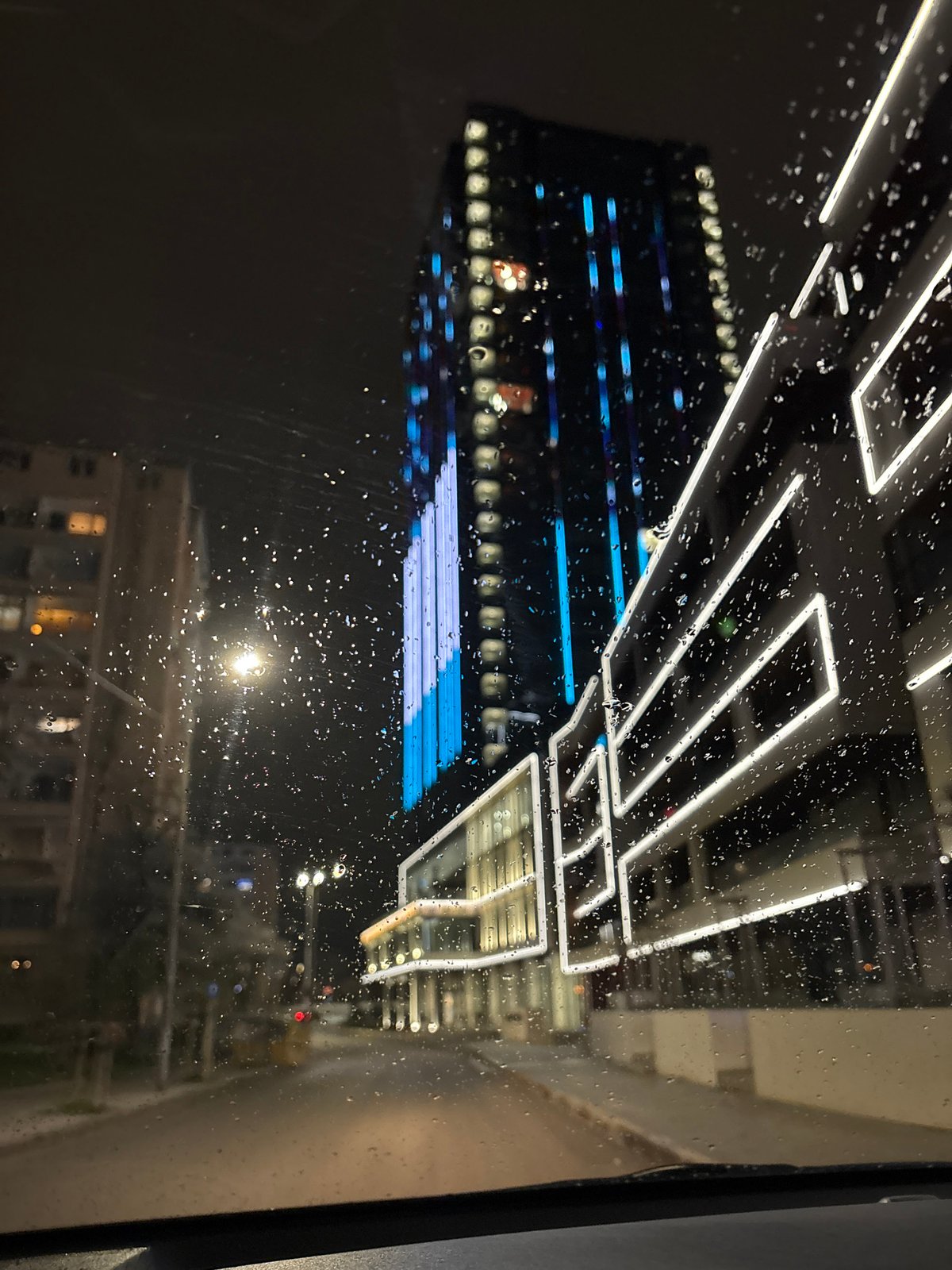 Rainy night view of illuminated modern building in Sofia