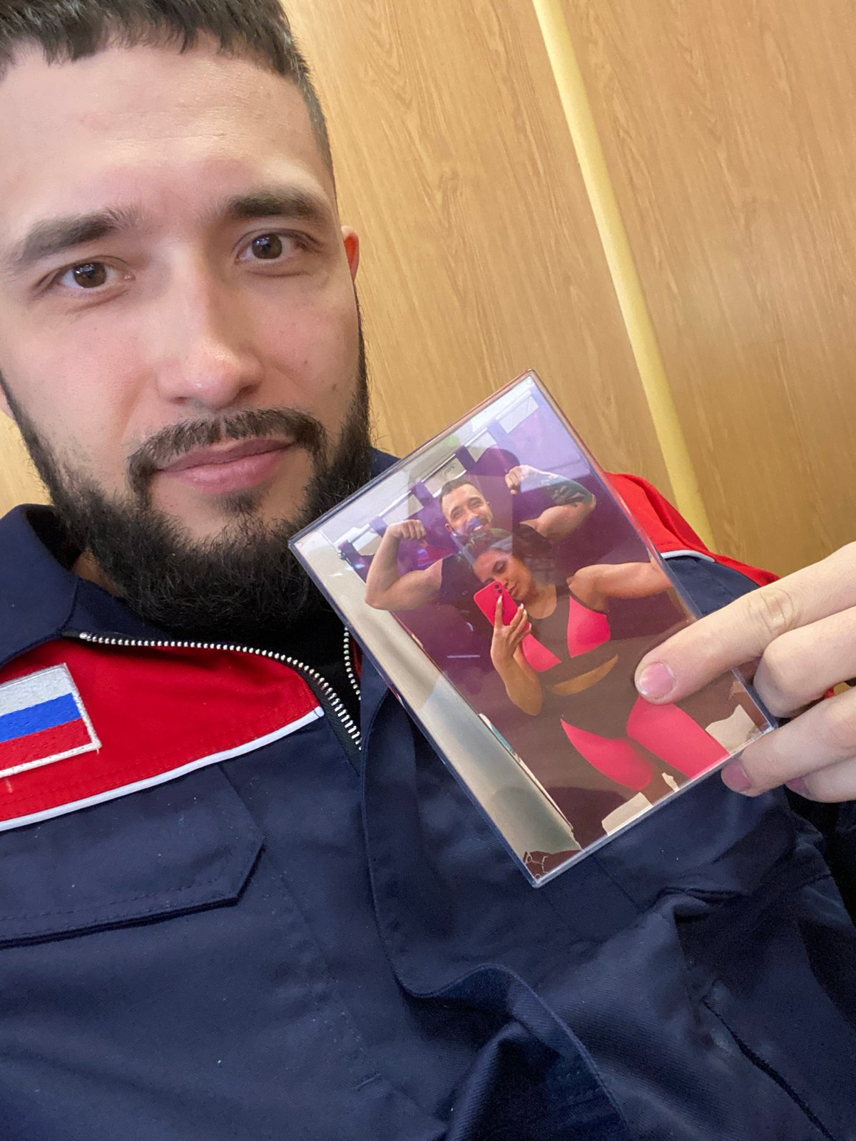 Man with Russian flag jacket holds photo in Luzhitsy