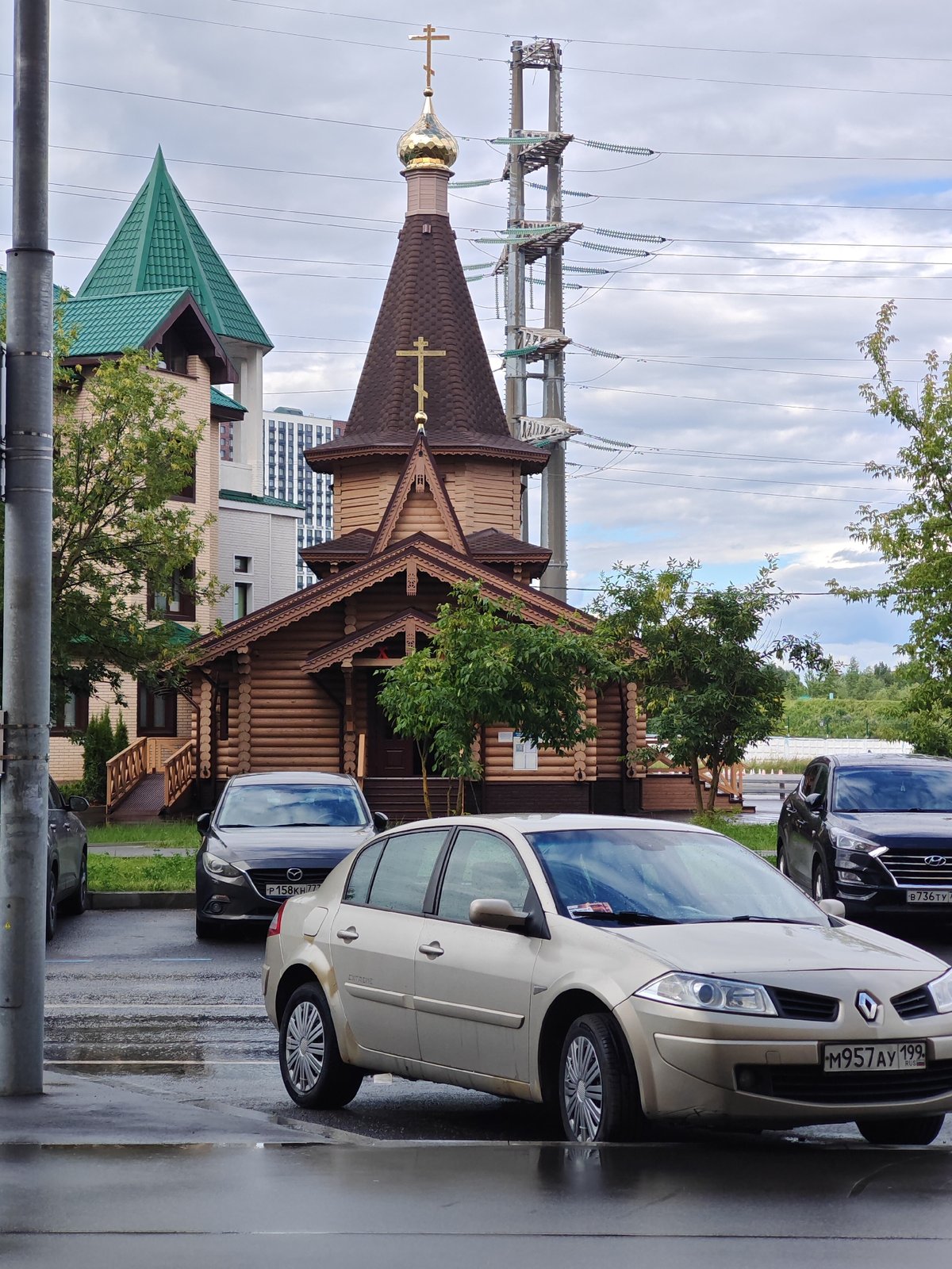 Wooden Orthodox church alongside modern brick building in Moscow