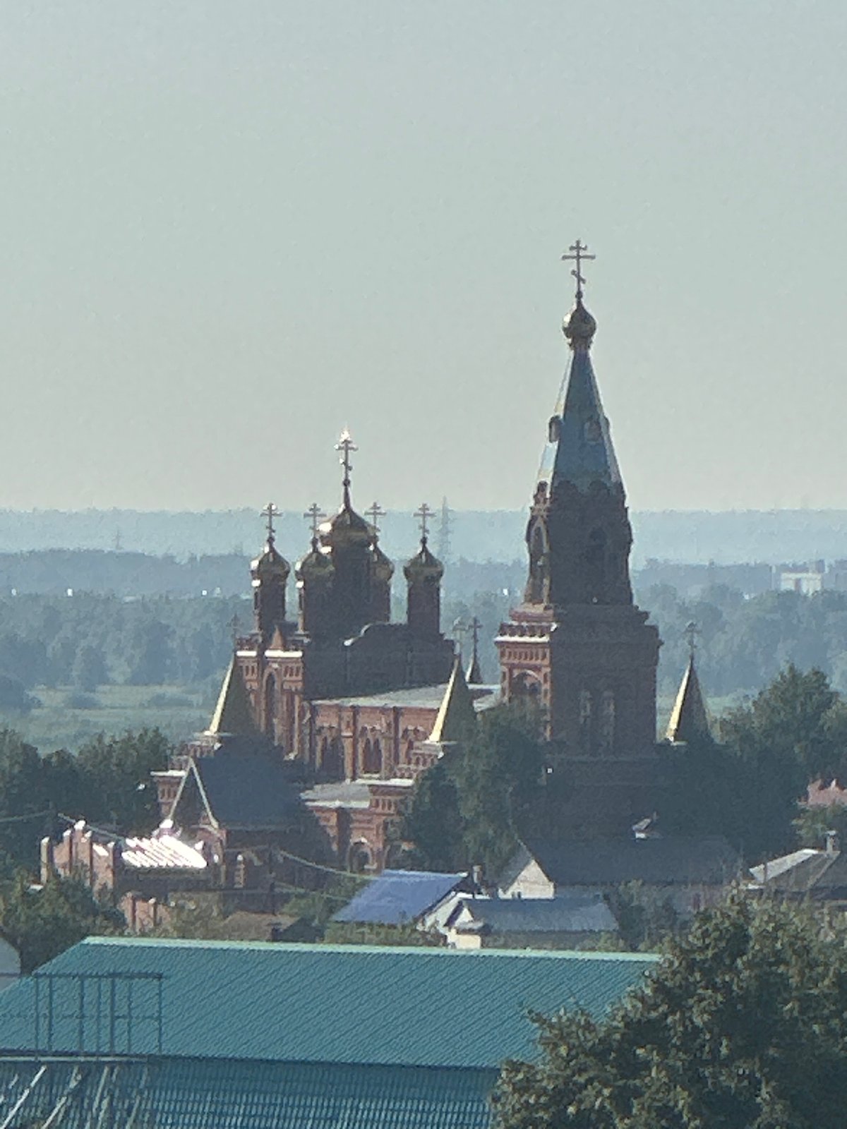 Red brick Orthodox church with golden domes overlooking a city