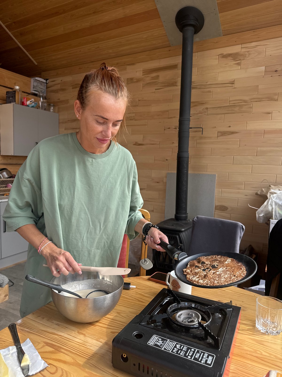 Woman cooks pancakes in early morning kitchen in Russia