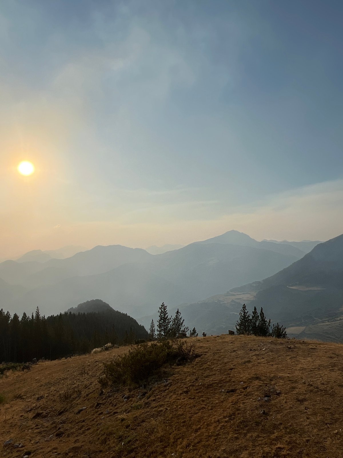 Hazy sunset over the Pyrenees, possible wildfire smoke in the air
