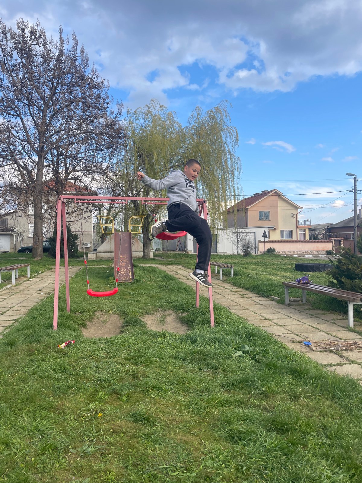 Young acrobat performs stunts on swing set in Bulgarian park