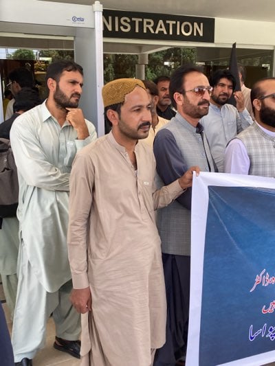 Men gather at institutional building entrance in apparent demonstration