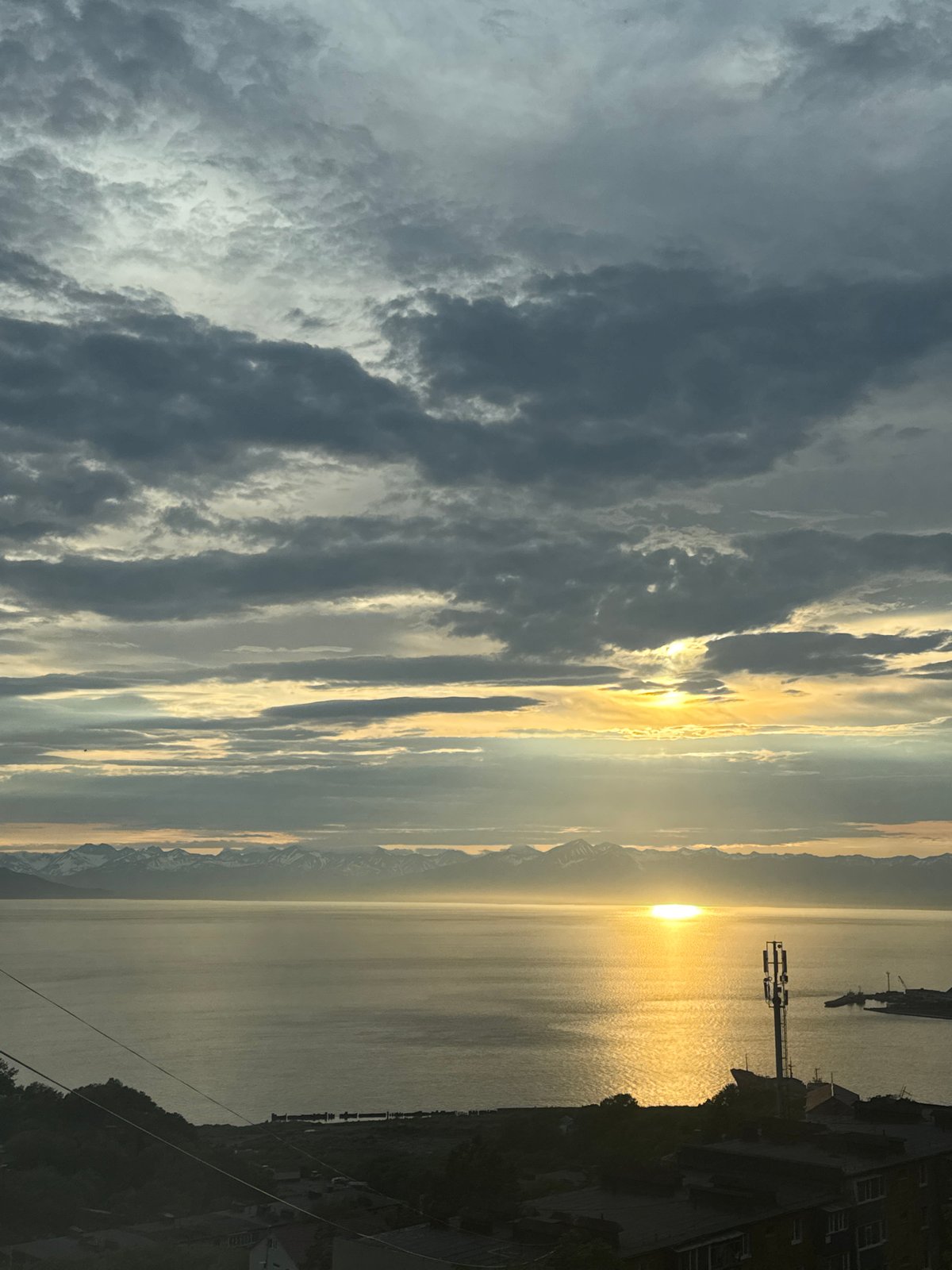 Stormy sunset over water with a mountainous horizon