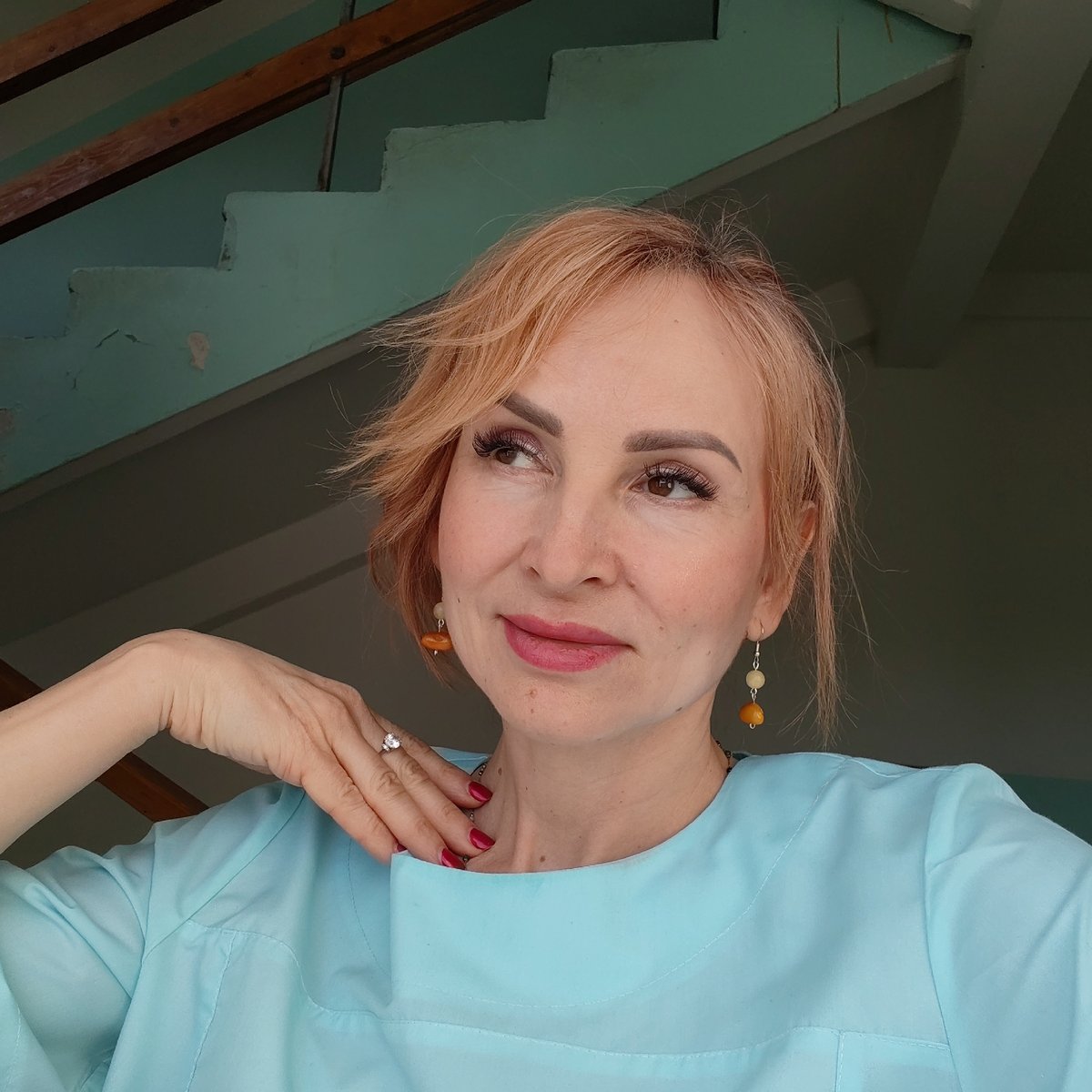 Woman in blue garment with beaded earrings gestures