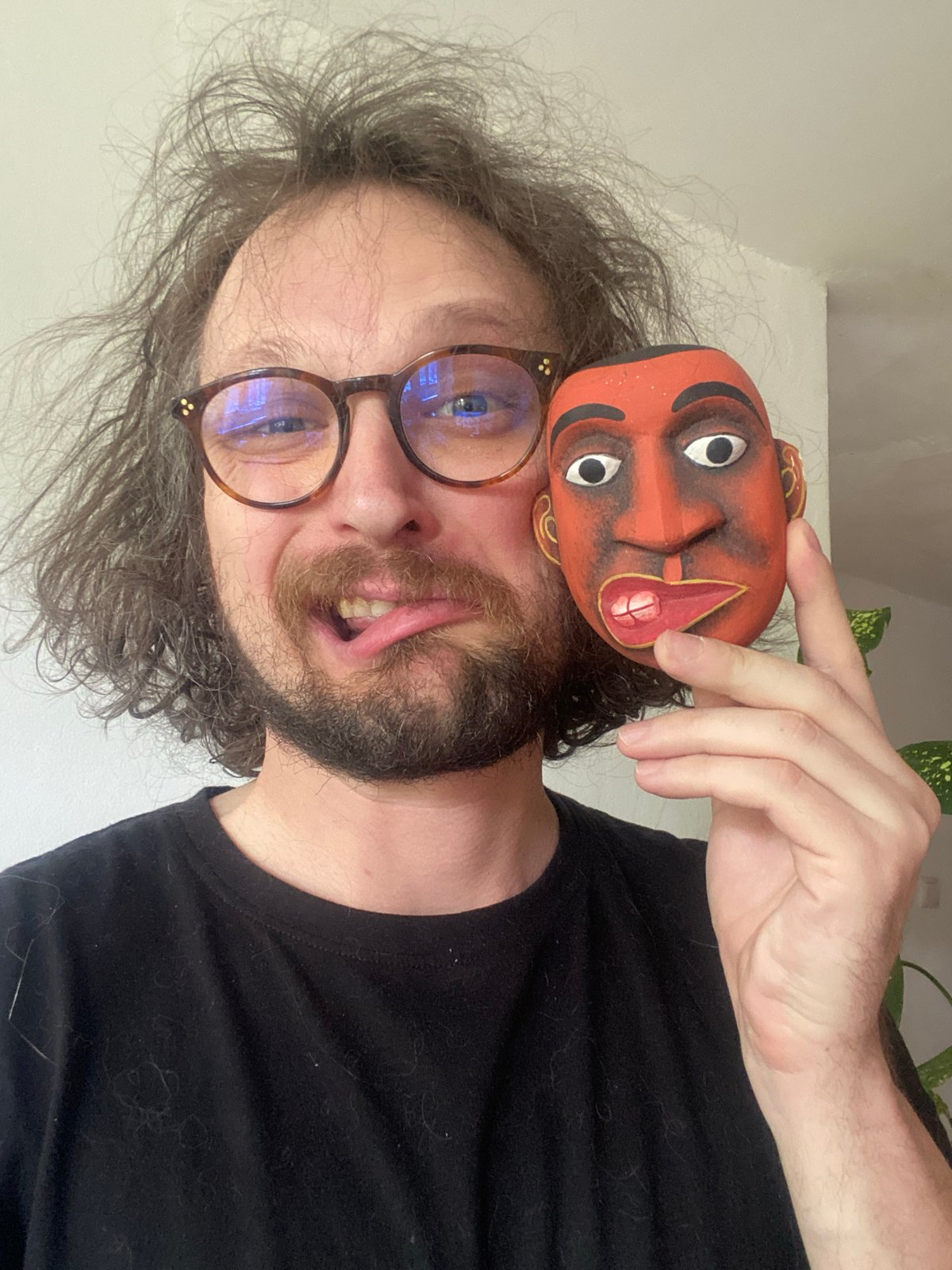 Person poses with decorative mask, personal items in Rusanovo