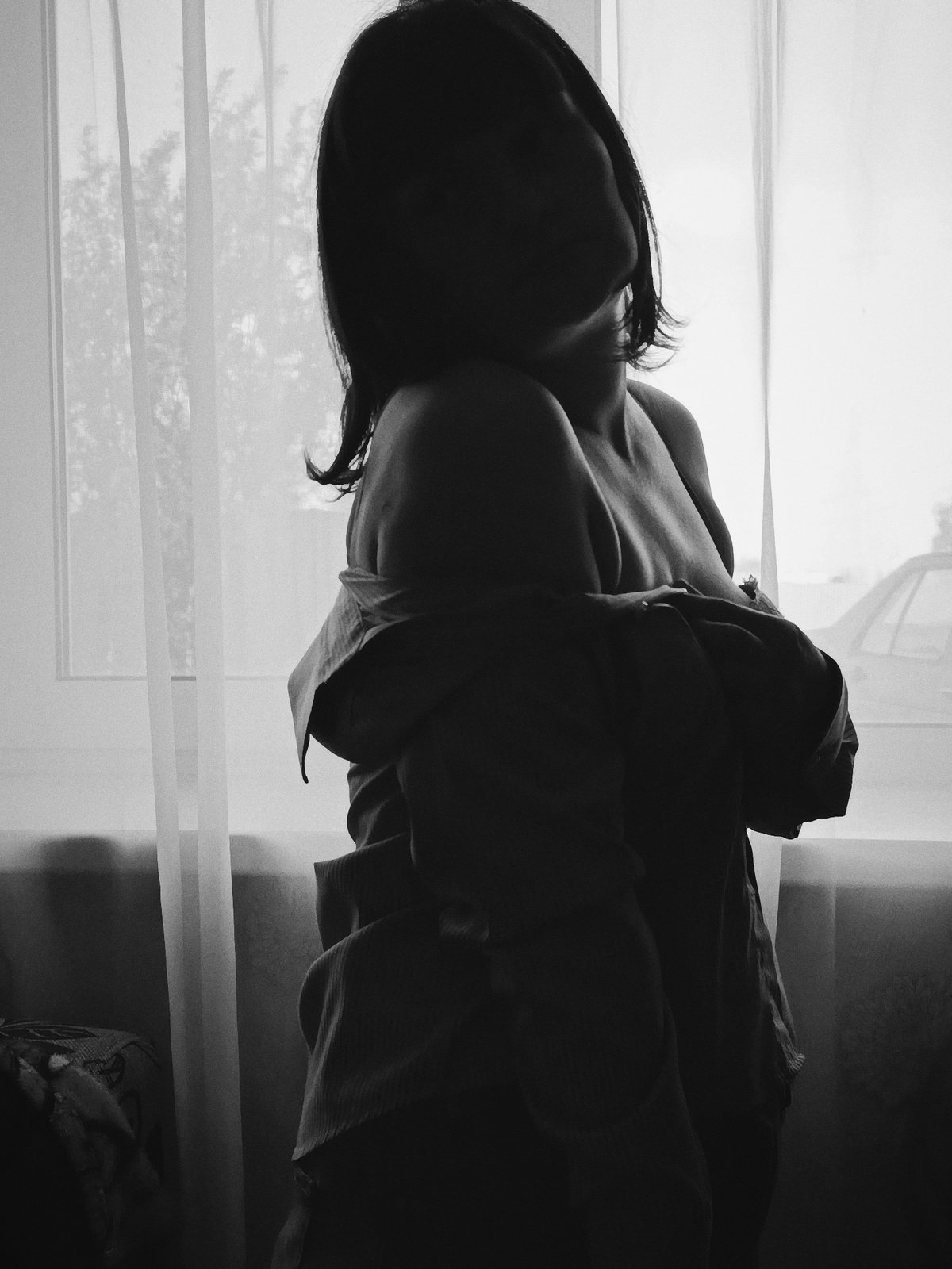 Black and white photograph shows woman by window