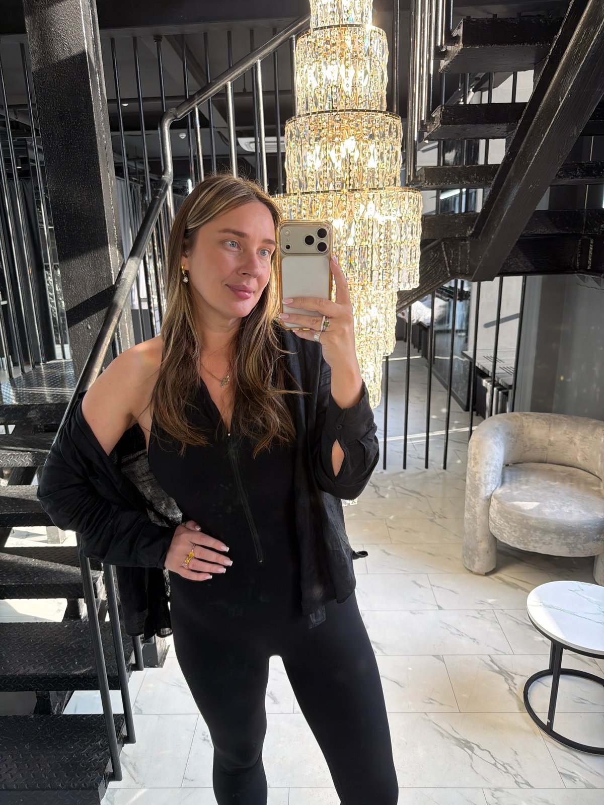 Woman takes selfie on staircase near chandelier in Moscow