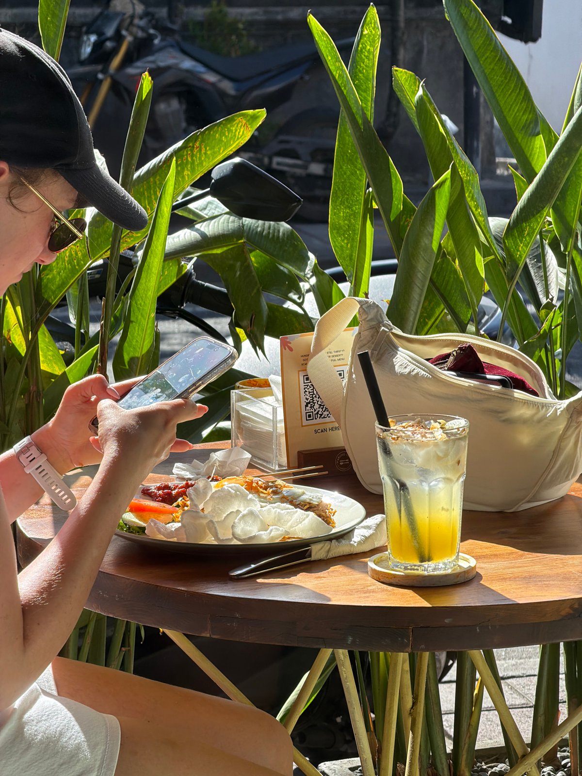 Diner photographs meal at plant-surrounded table in North Kuta