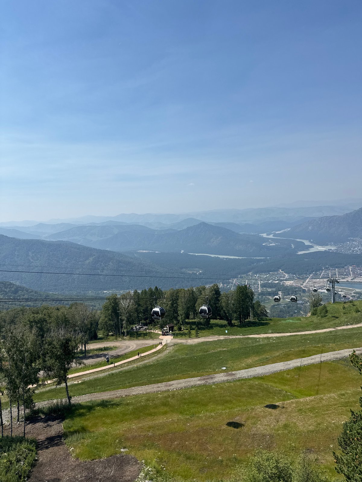 Gondola lift crosses green mountain terrain above Ozernoe, Russia