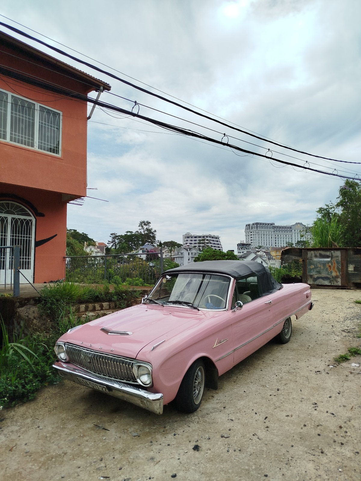 Vintage cars and scooter gather near colorful buildings in Da Lat