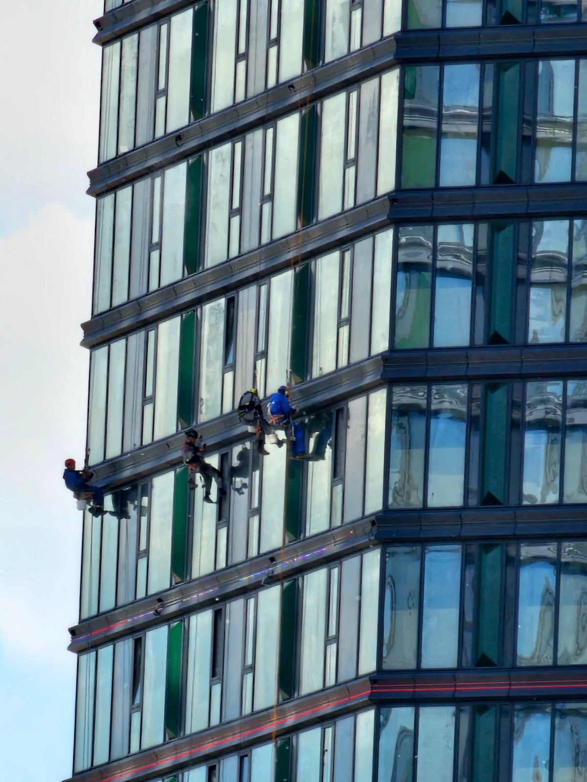 Window cleaners work Moscow skyscraper as luxury cars park below