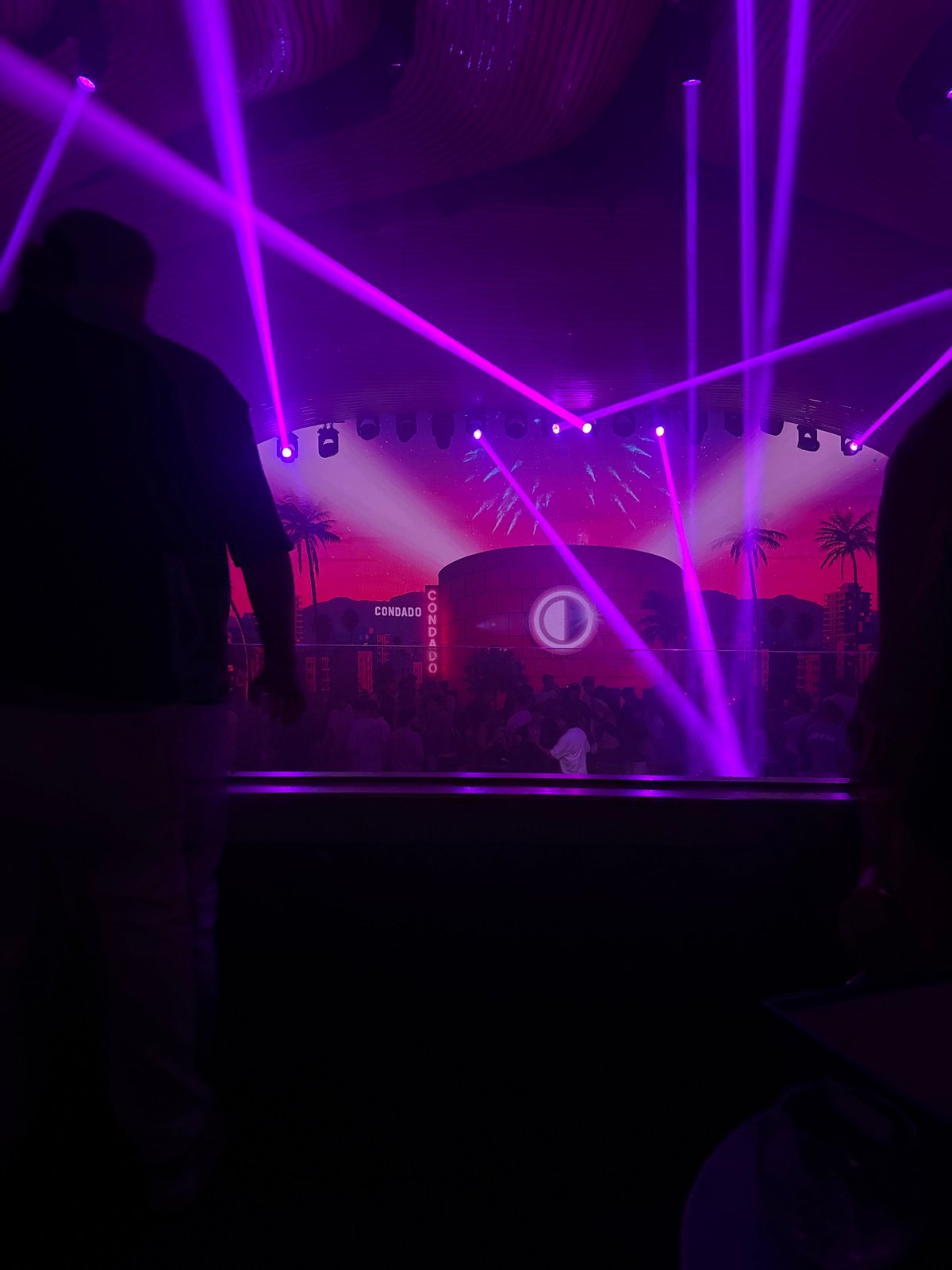 DJ set underway at a packed nightclub with laser lights