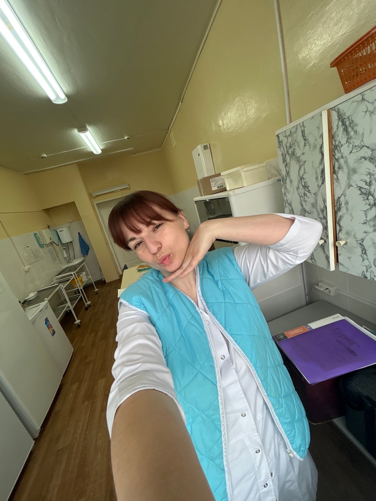 Woman takes indoor selfies in quilted vest in Фоки, Russia