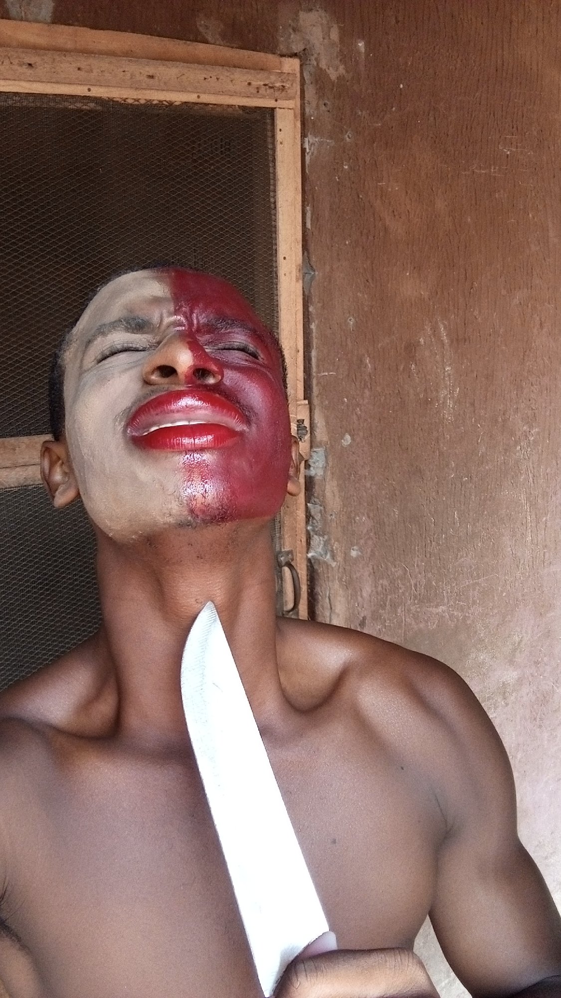 Person performs dramatic knife-to-throat act with split face paint