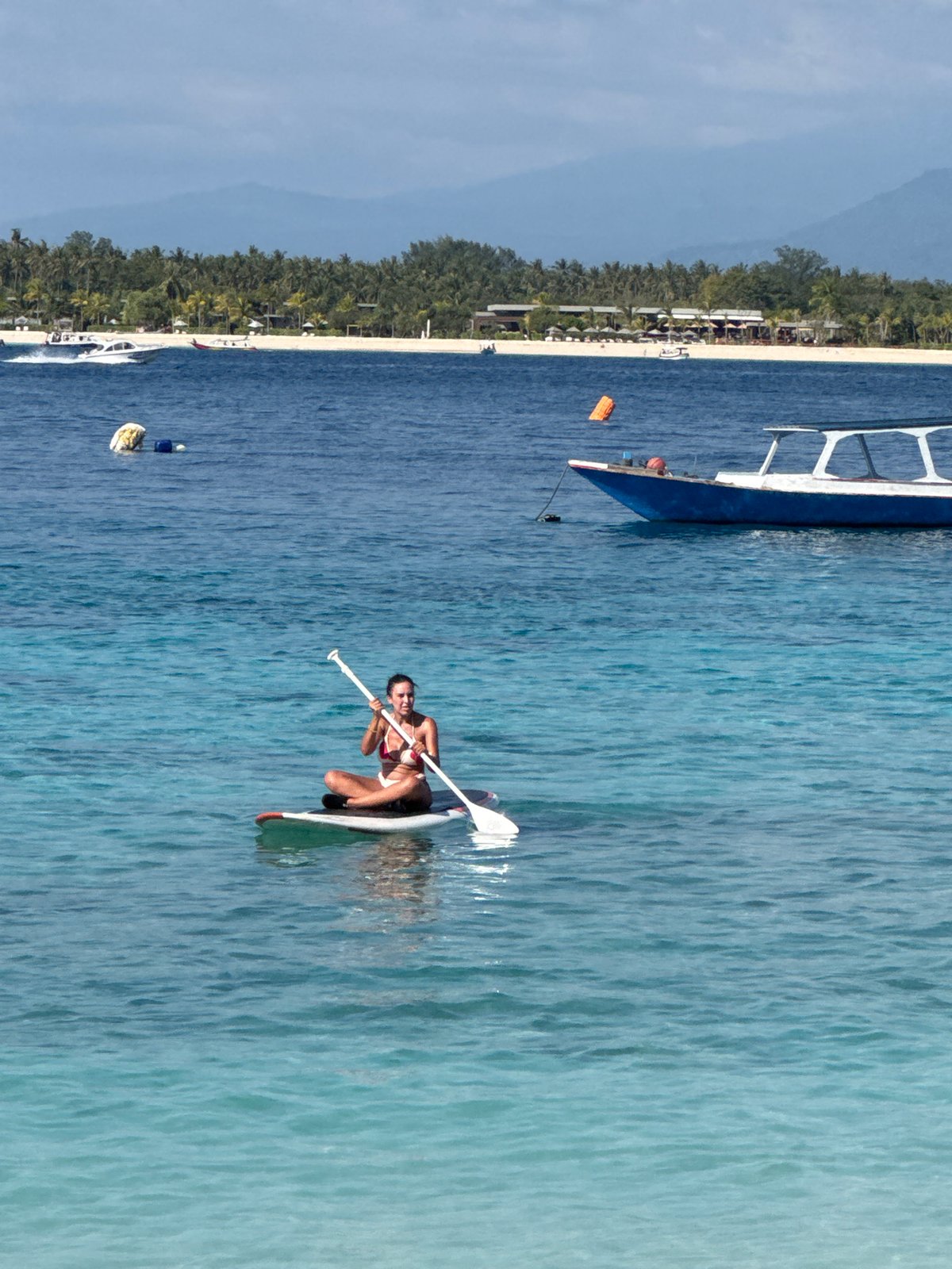 A laid-back Indonesian beach day with boats, snorkelers, and sun