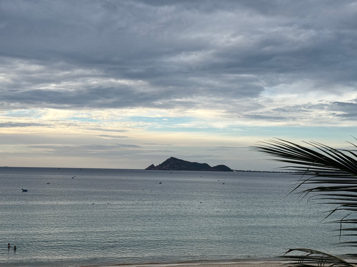 Overcast dusk over a calm bay with a forested hillside