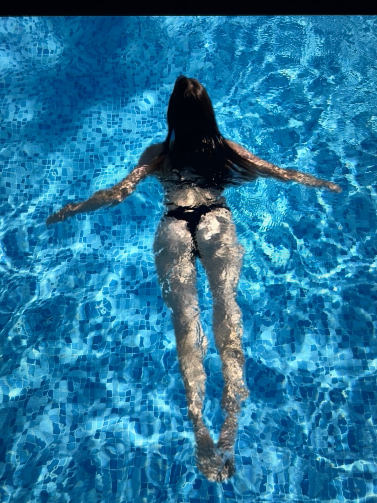 Floating on back in a blue tiled swimming pool