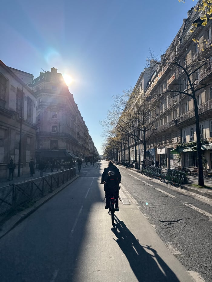 Cyclist observed on Paris street during bright afternoon sun