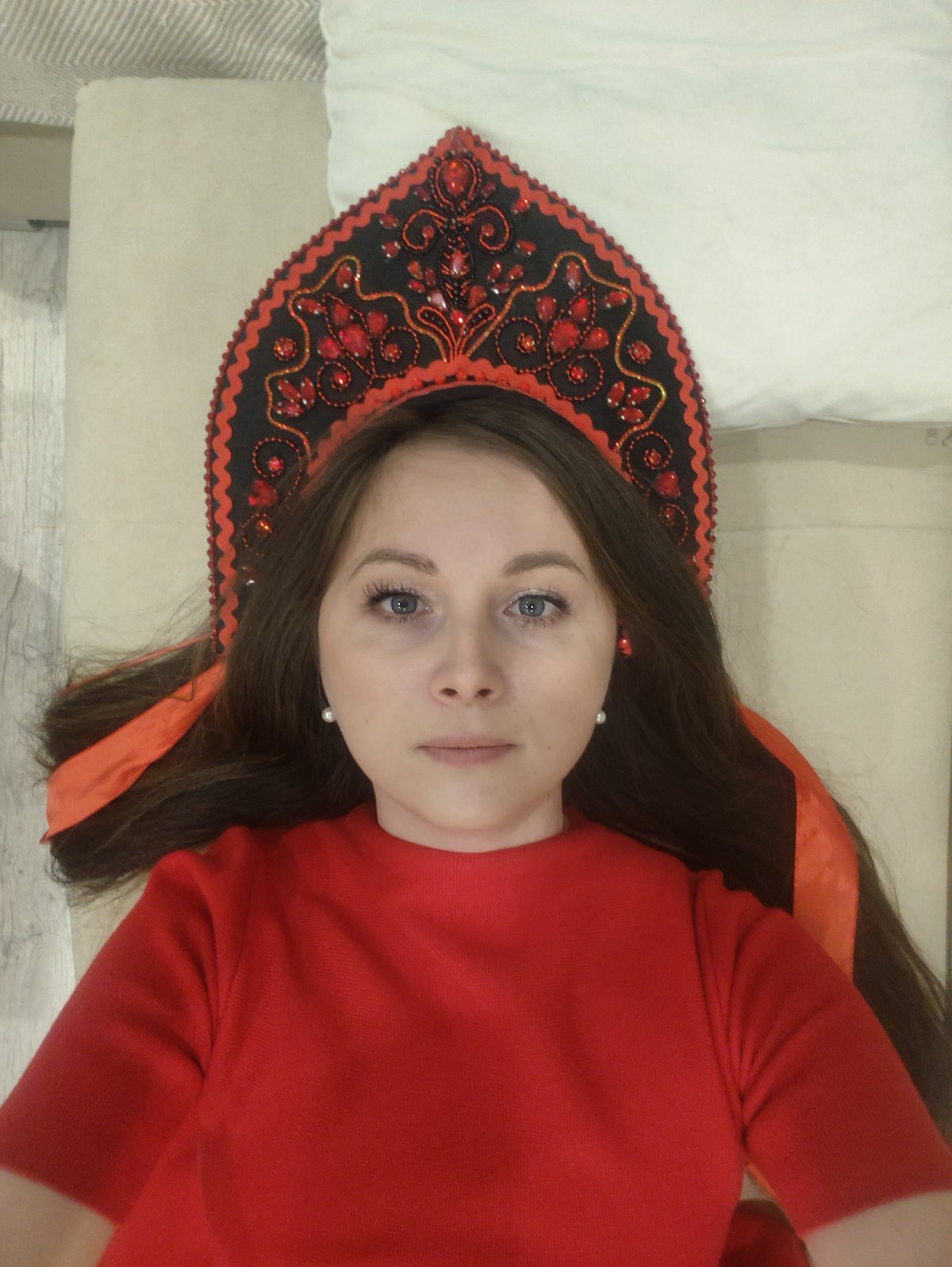 Woman in ornate headdress rests on beige surface