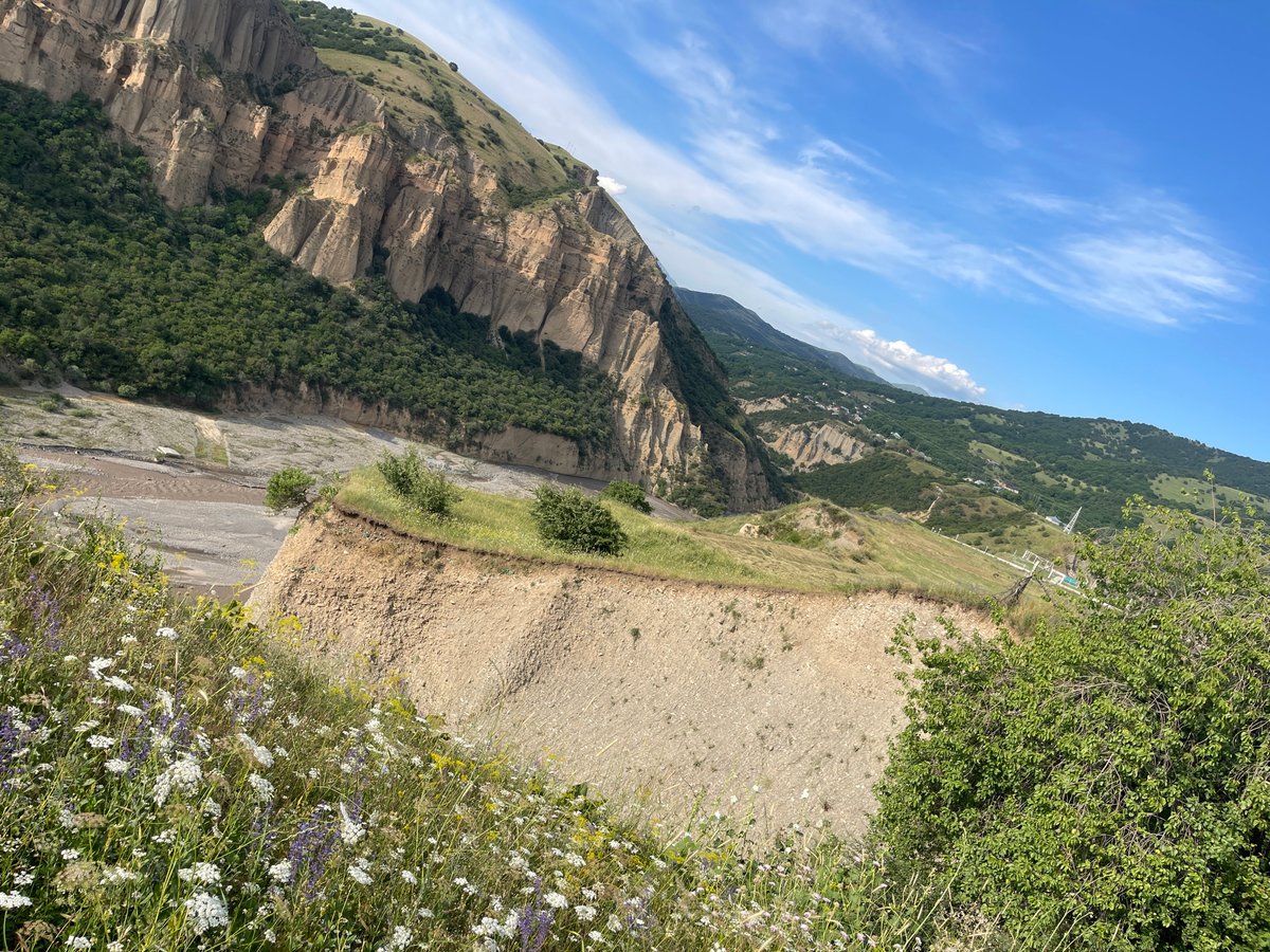 Cliffs, fields, and wildflowers across Taran-Bazar's rugged valley
