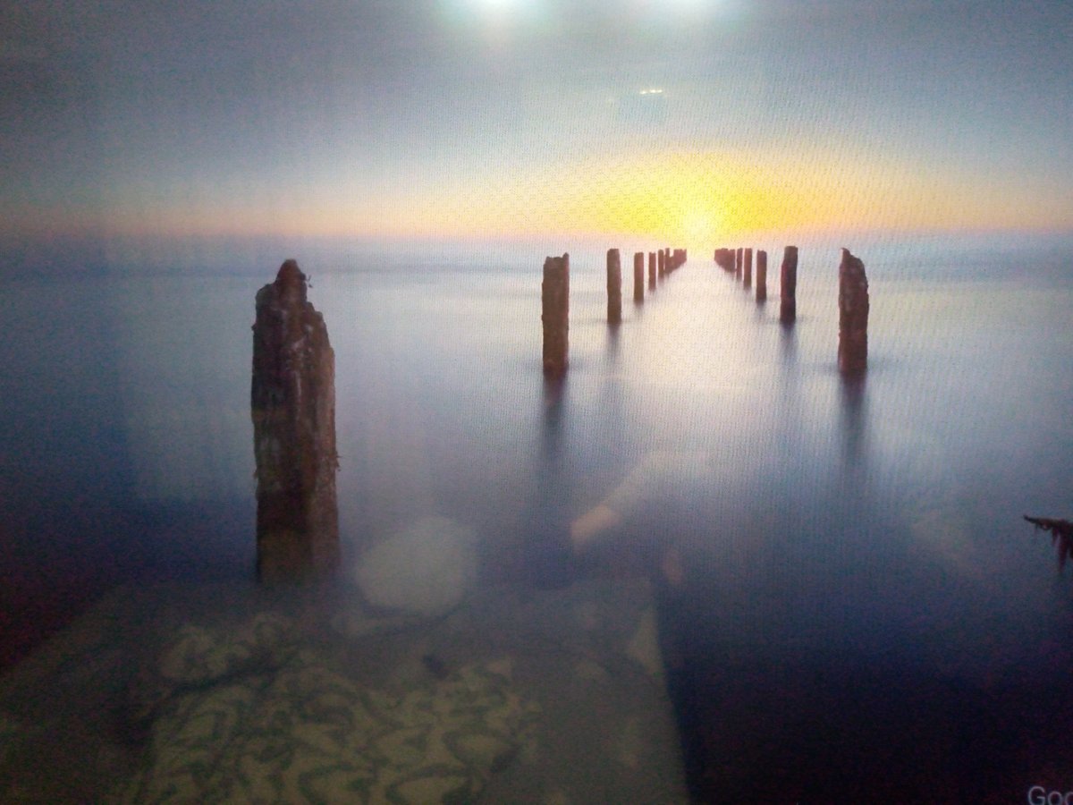 Weathered pilings stand in a hazy Black Sea sunset near Sochi