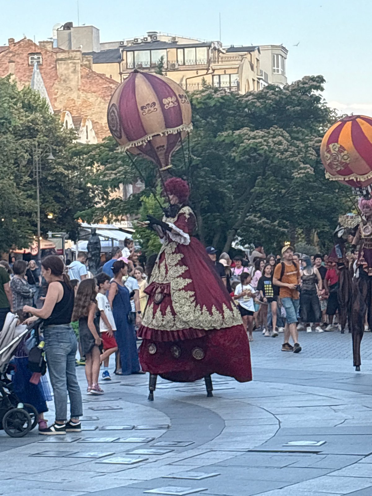 Stilt performers and a bear costume character work a city plaza crowd