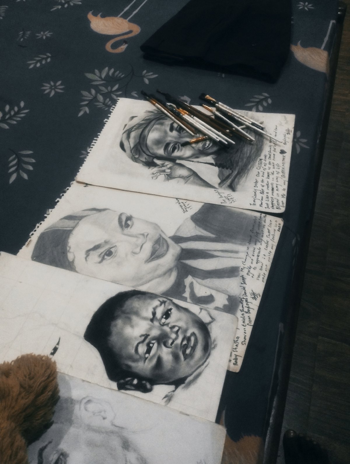 Charcoal portrait sketches displayed on patterned fabric during art session