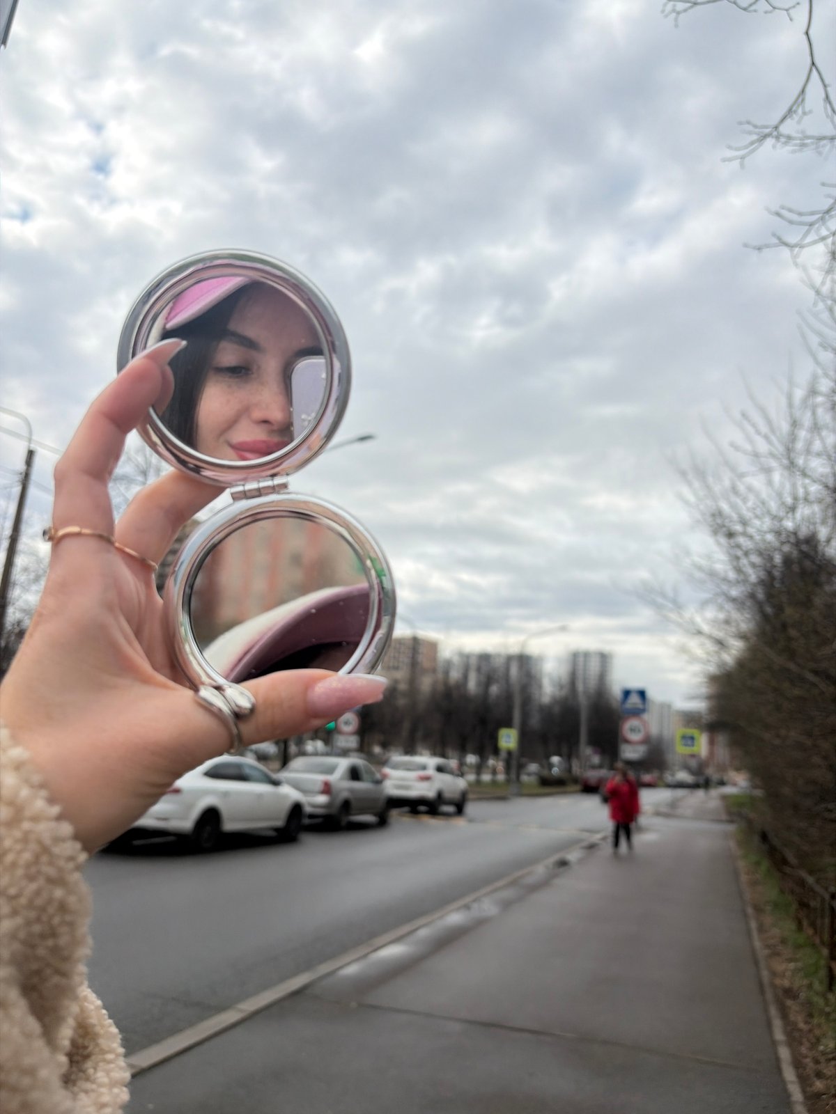 Woman checks reflection in compact mirror on Saint Petersburg street