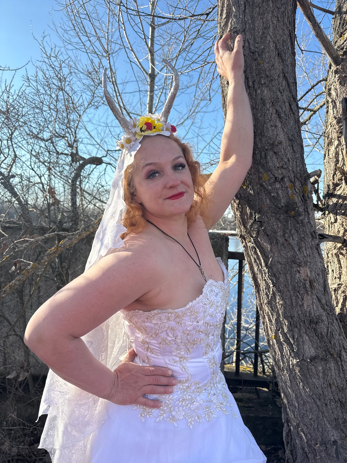 Woman in horned floral crown poses on trees in Russian forest