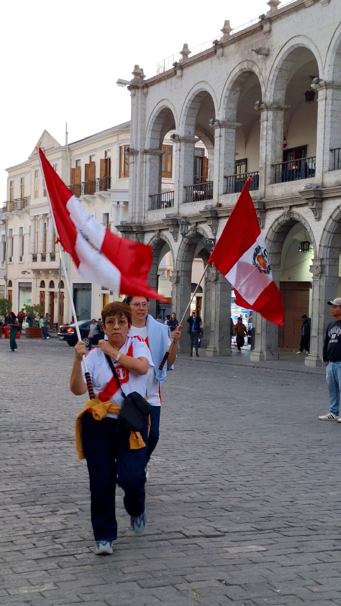 Two people display Peruvian flags in Arequipa plaza