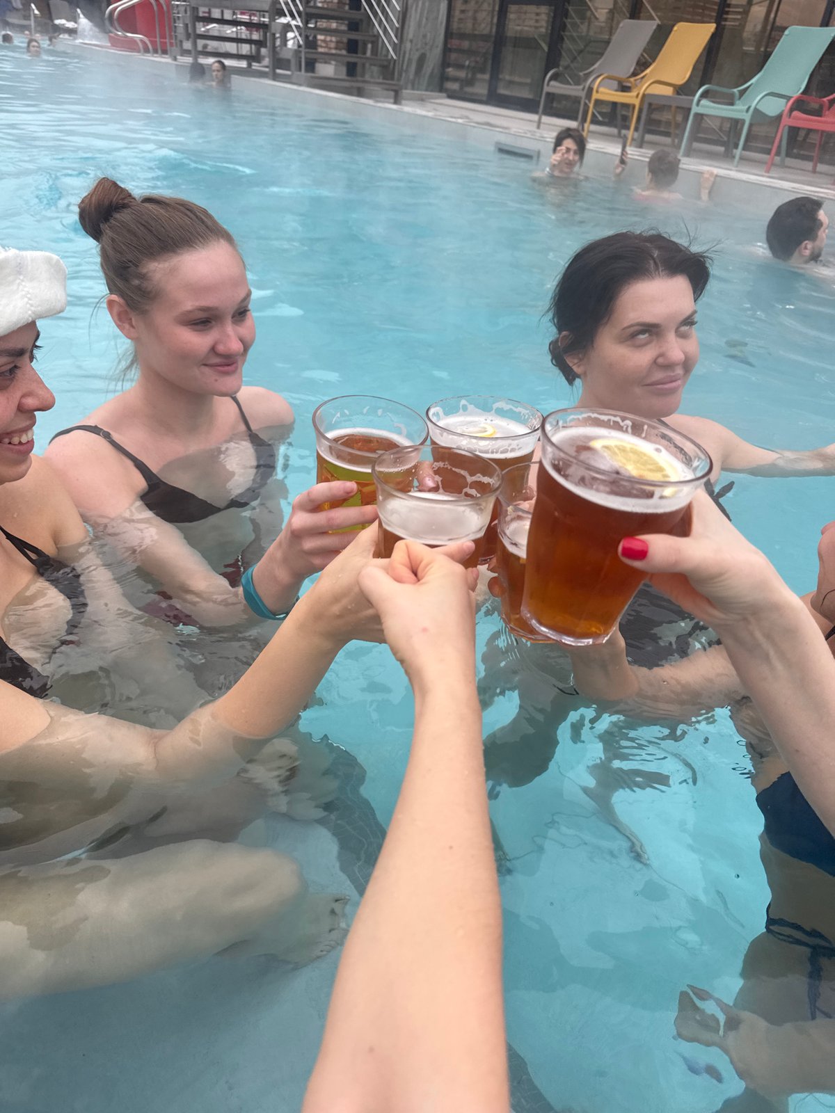Women toast with drinks in Moscow indoor pool