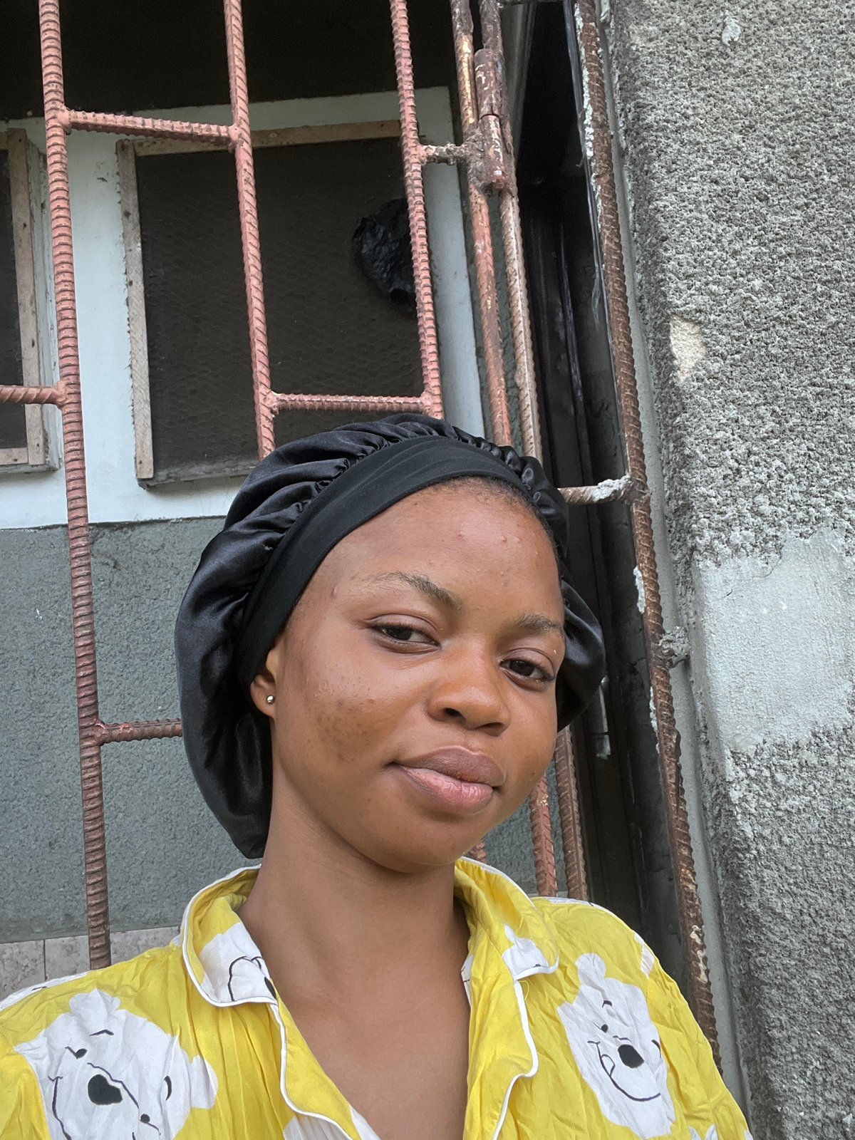 Woman in black bonnet collecting water in Lagos