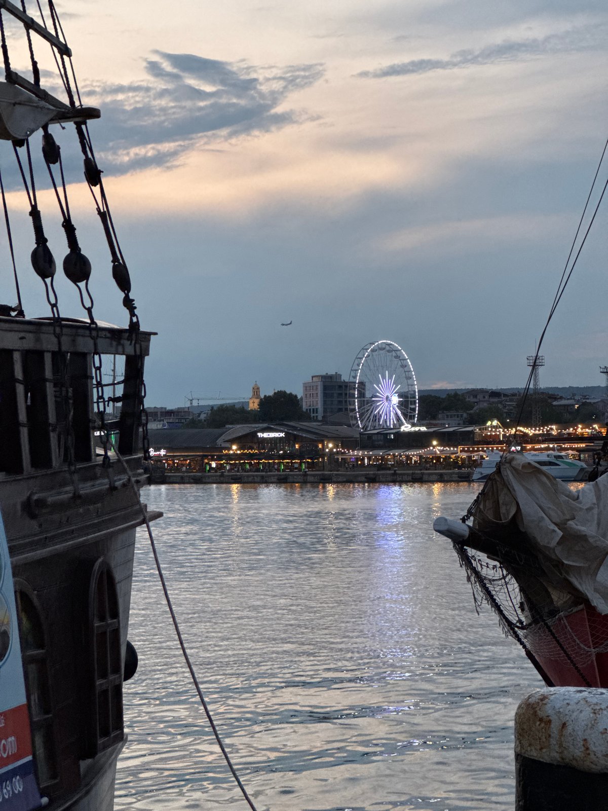 Varna harbor at dusk: tall ships, scooters, and sunset light