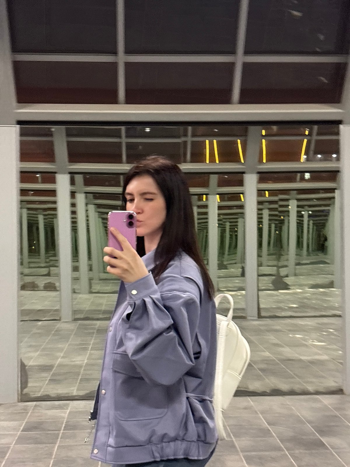 Woman captures selfies in mirrored Moscow spaces near astronaut mural