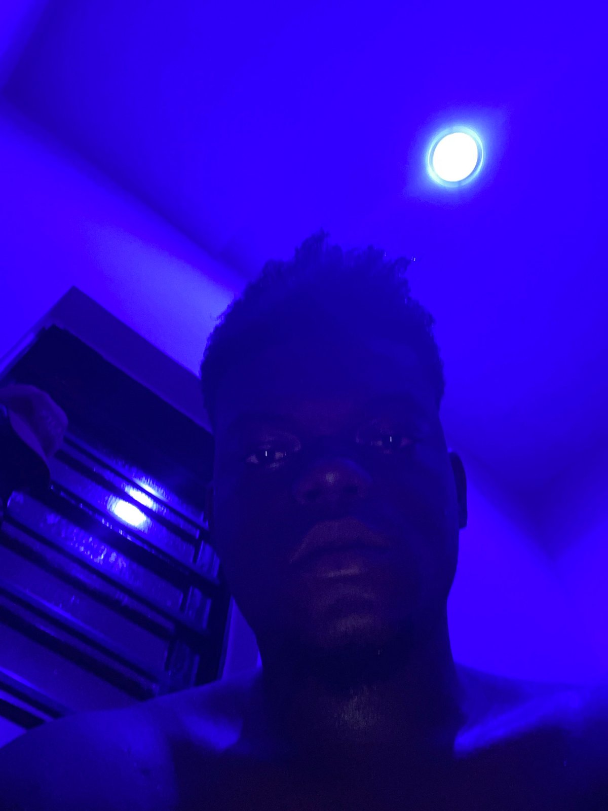 Person photographed under blue lighting looking downward