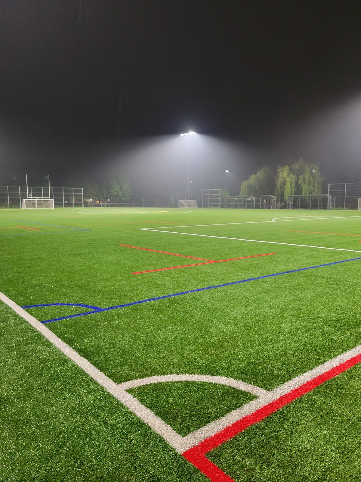 Empty Montreal soccer field glows under stadium lights in the rain