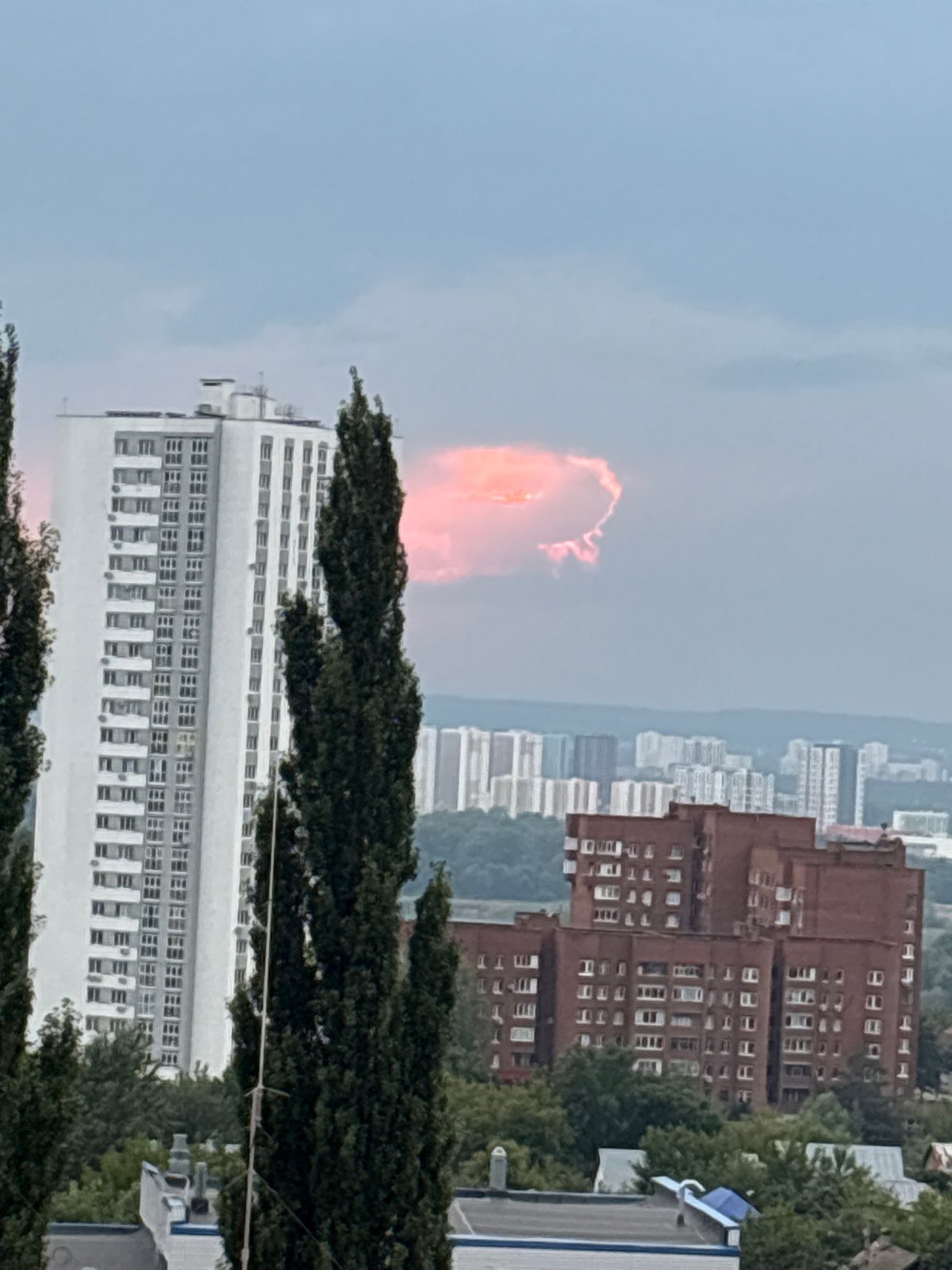 Ufa skyline with striking pink-orange clouds over city trees