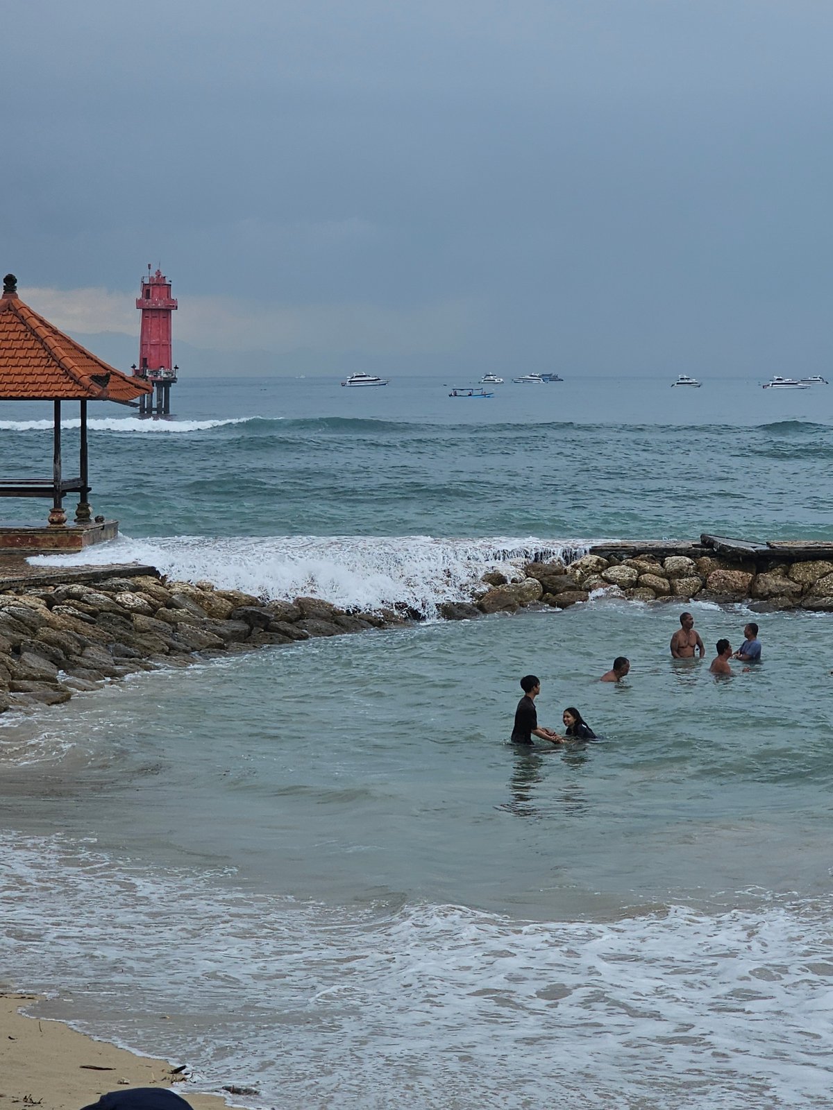 Temple visitors and boats observed at Denpasar coastline