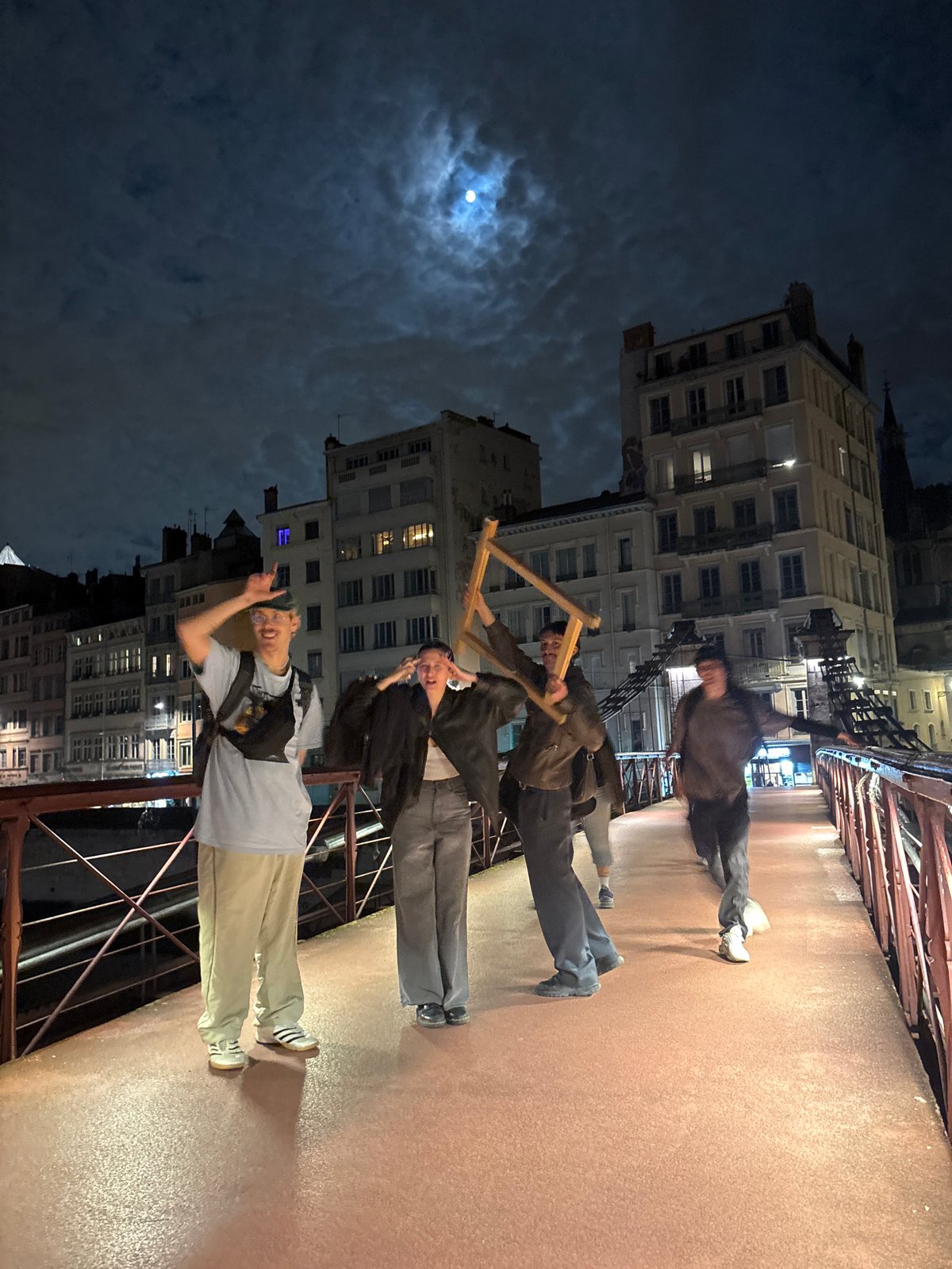 Young men pose for nighttime photos on Lyon bridge