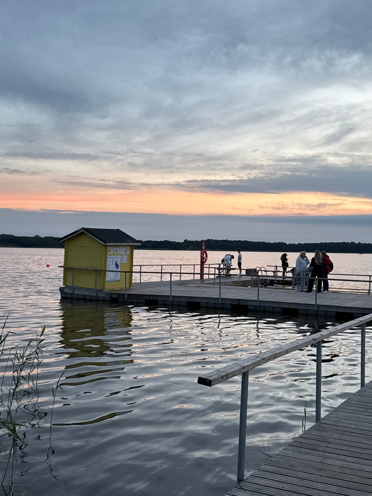 Summer evening gathering on a Tallinn lakeside pier at sunset