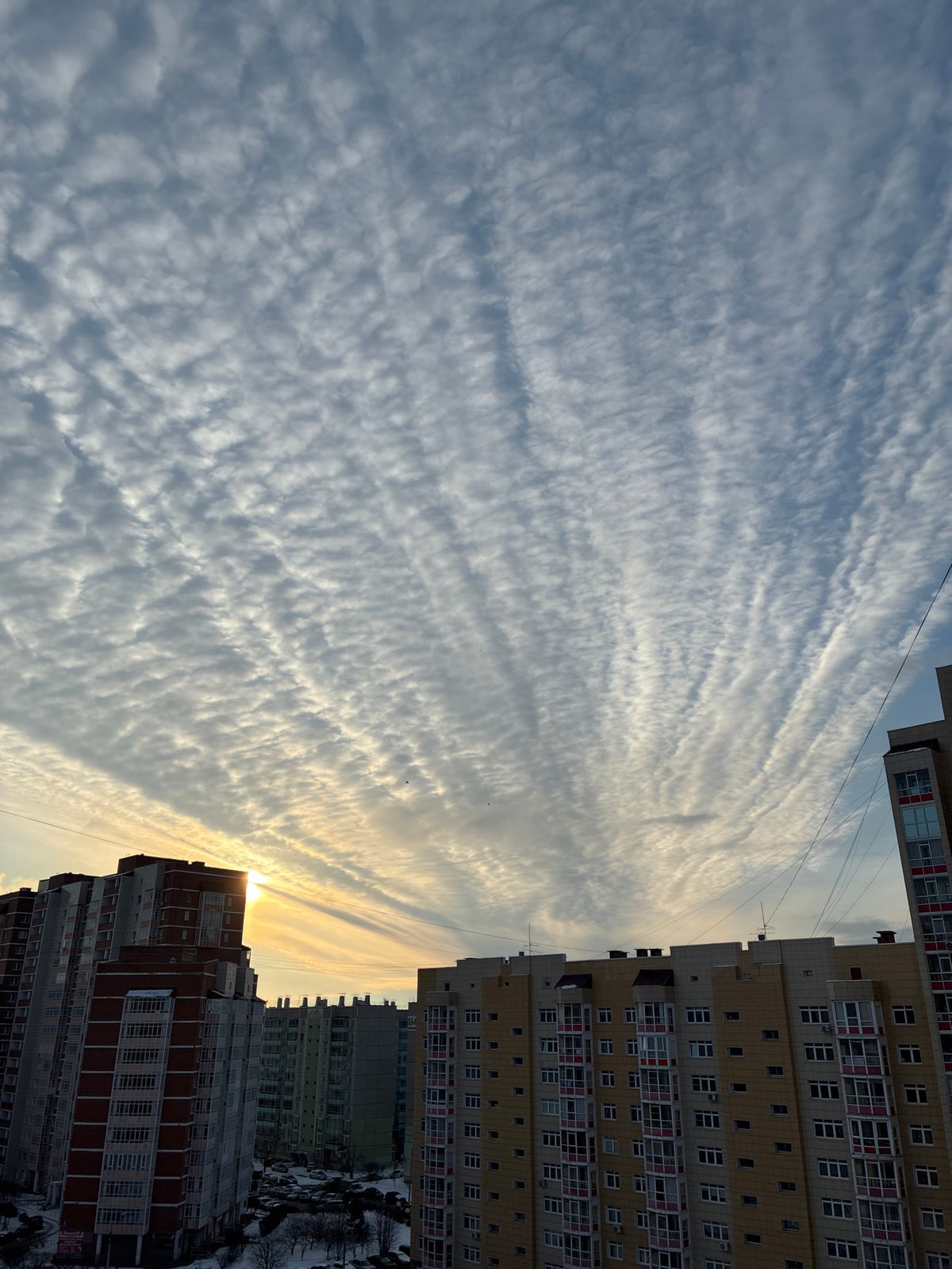 Urban skyview between apartment buildings shows striated clouds overhead