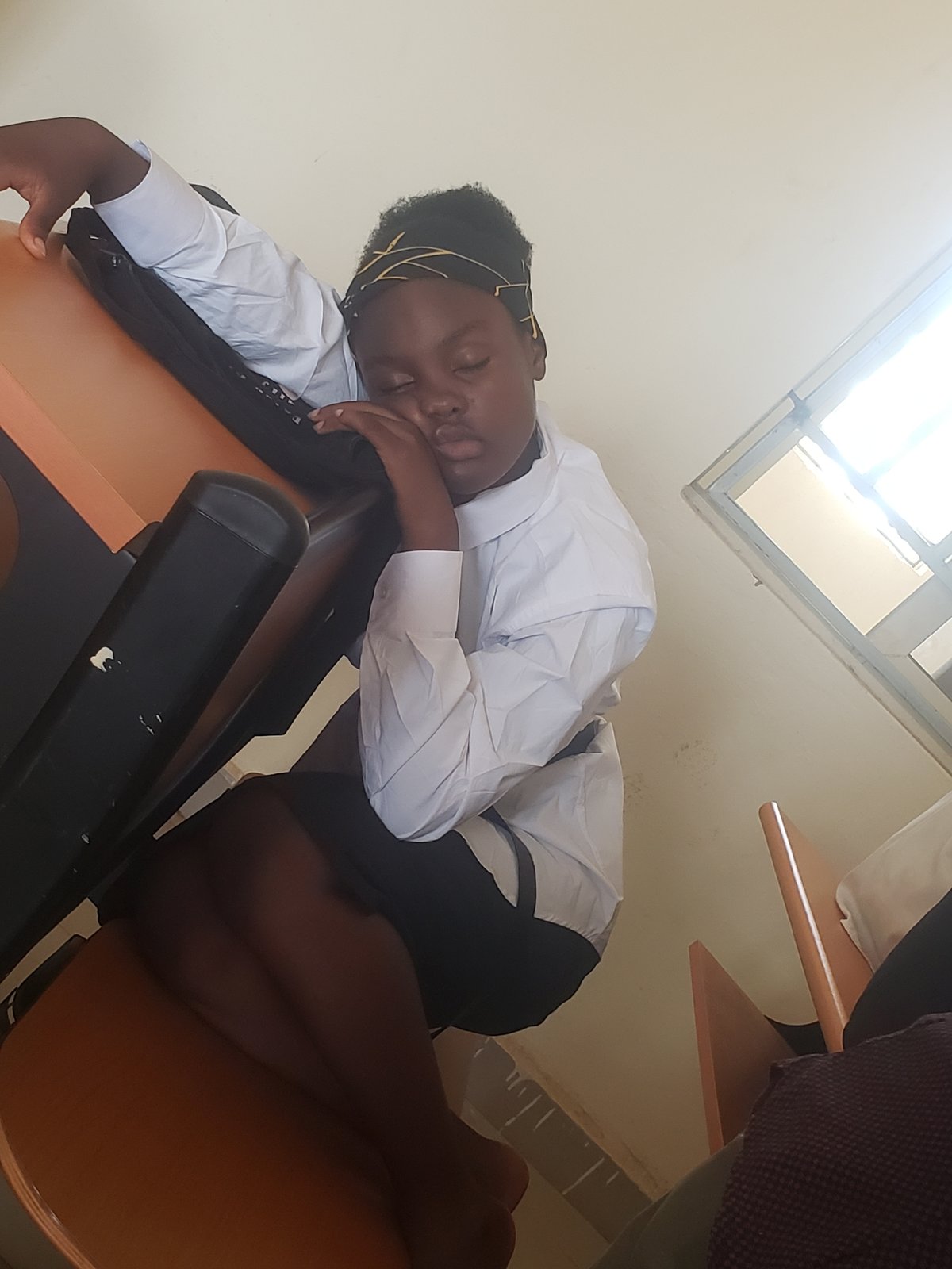 Students rest and use phones during classroom break in Gumel