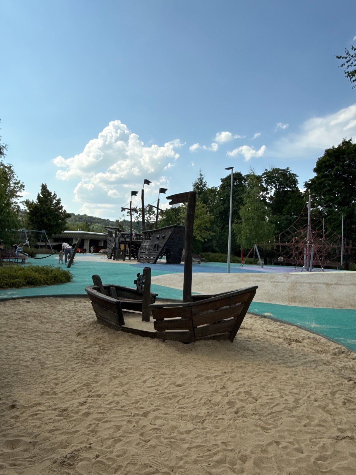 Riverside park scenes: playground, gardens, boat, and city views