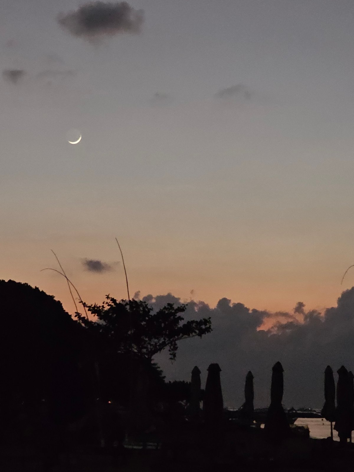 Sanur Beach at dusk: boats, a glowing gazebo, and twilight skies