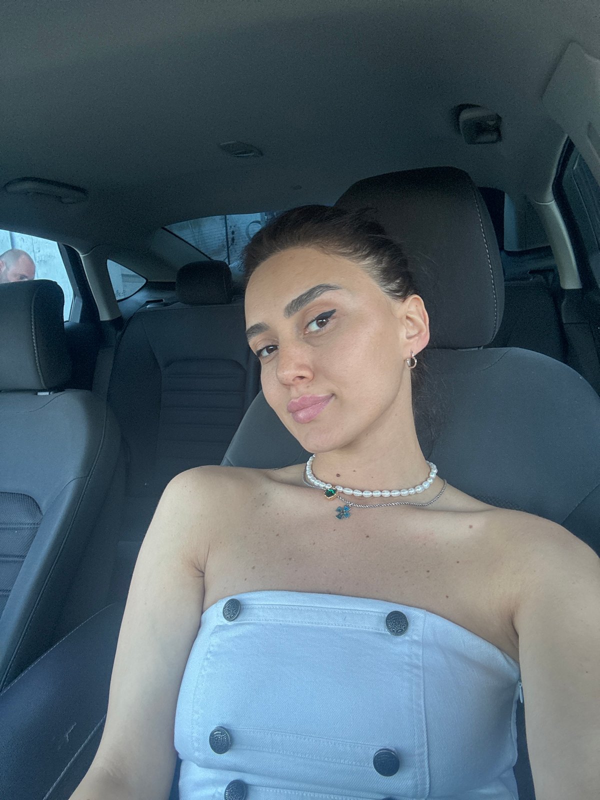Driver in car wearing white top and pearls, Tbilisi