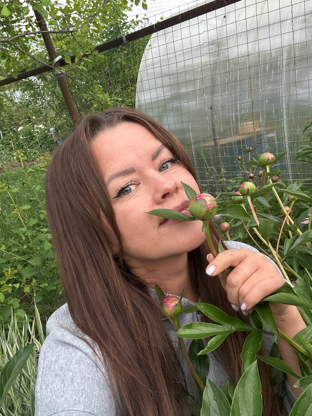 Woman poses with peonies amid dramatic skies in Chaikovsky